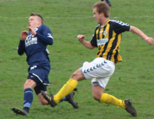 Michael Edvoldo Sørensen, Brønshøj Boldklub, sætter en veltimet tackling ind mod en LFA-spiller i Brønshøjs udekamp mod Lolland-Falster Alliancen 12. maj 2010 (foto: T. Brygger)